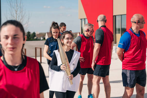 Une relayeuse portant la torche olympique s'apprête à s'engager devant la CIME